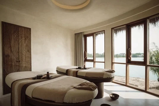 Twin spa treatment beds beside floor-to-ceiling windows overlooking the river